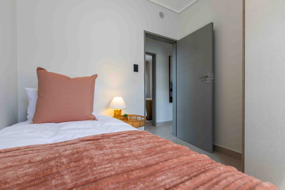 A well-maintained bedroom featuring tiled flooring, a built-in cupboard, and a modern grey internal door, offering a clean and neutral living space.