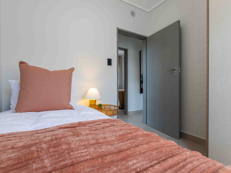 A well-maintained bedroom featuring tiled flooring, a built-in cupboard, and a modern grey internal door, offering a clean and neutral living space.