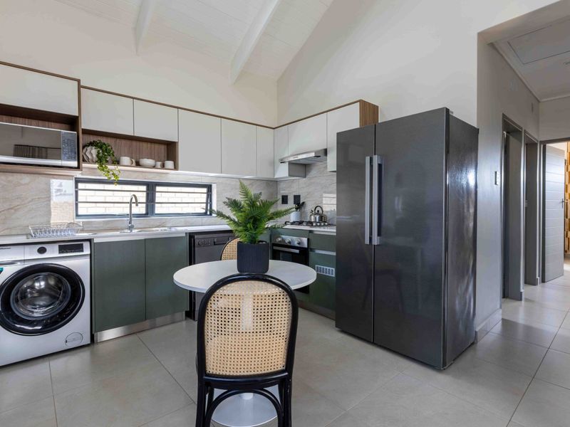 Modern kitchen featuring sleek cabinetry, stone-look backsplash, built-in appliances, and vaulted ceilings, creating a bright and functional culinary space.