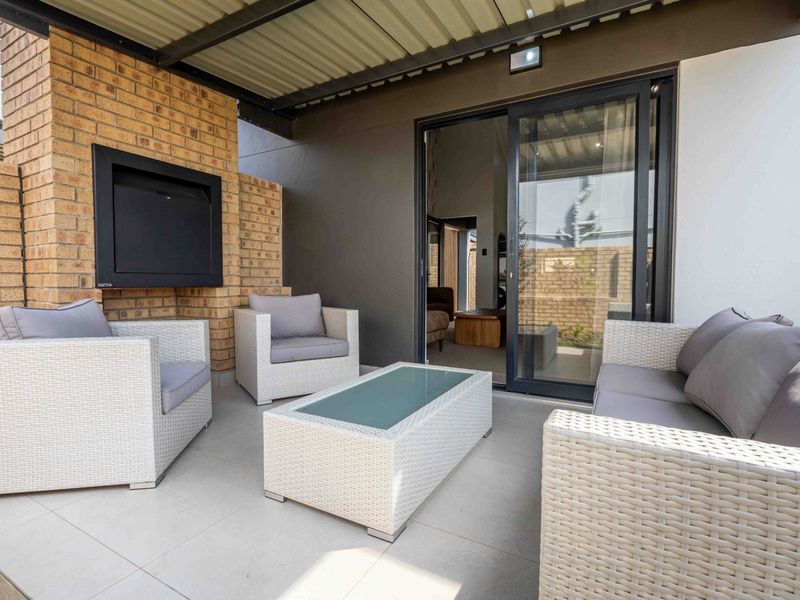 A modern covered patio featuring tiled flooring, a built-in fireplace, and sliding glass doors providing seamless access to the interior living space.