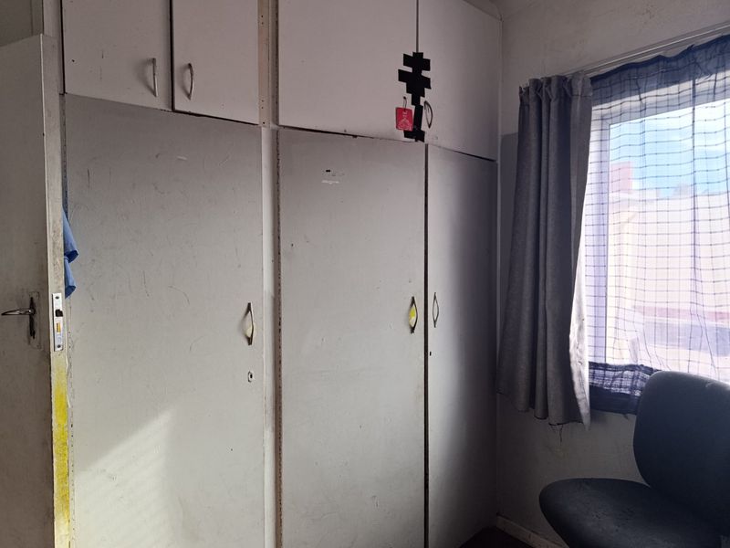 A bedroom featuring built-in cupboards with visible wear and tear, requiring cosmetic updates to improve the overall aesthetic and condition of the space.