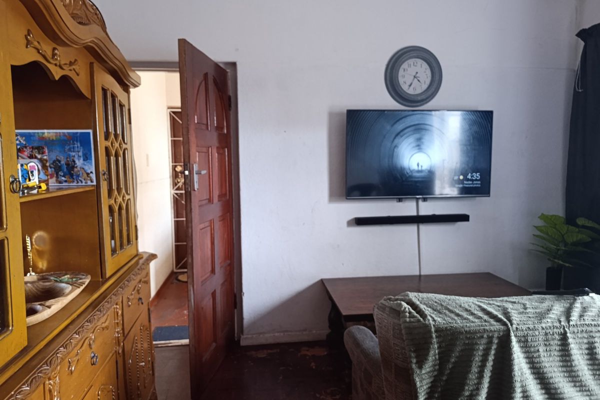A living room featuring hardwood flooring and a wooden door leading to an adjacent hallway.