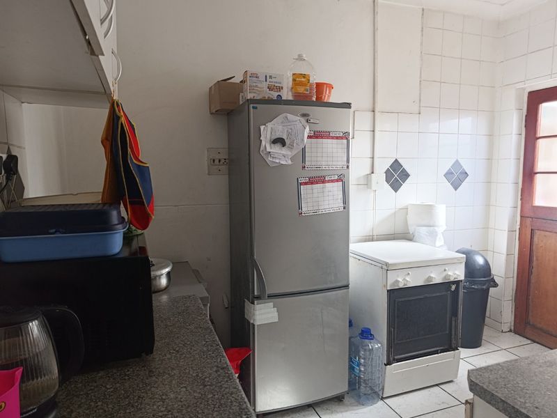 A functional kitchen area featuring tiled splashbacks, stone countertops, and a freestanding oven, requiring cosmetic updates to modernize the space.