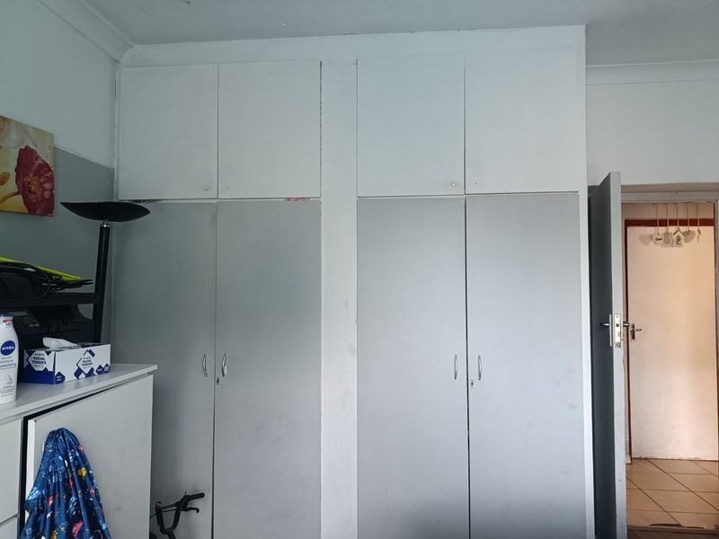 Bedroom featuring floor-to-ceiling built-in cupboards with overhead storage units, providing ample storage space.