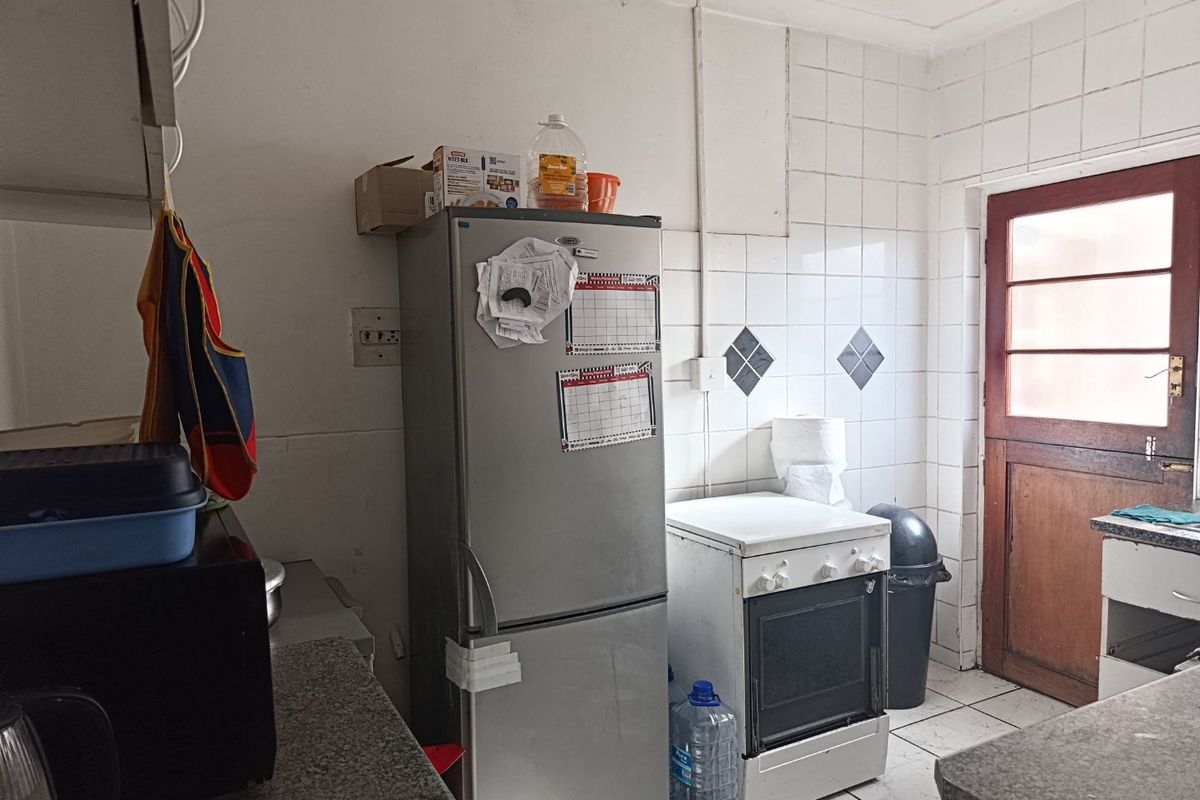A functional kitchen space featuring a freestanding oven, tiled splashback, and direct access to an exterior door.