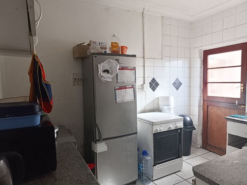 A functional kitchen space featuring a freestanding oven, tiled splashback, and direct access to an exterior door.