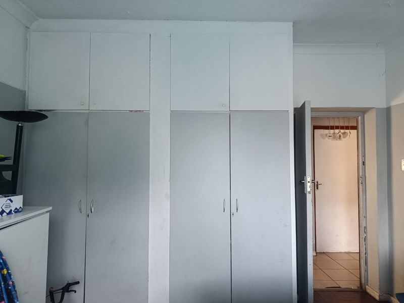 Bedroom featuring floor-to-ceiling built-in cupboards with overhead storage compartments and a doorway leading to an adjacent tiled area.