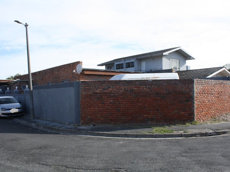 Street view of the property showing the corner boundary walls and surrounding infrastructure.