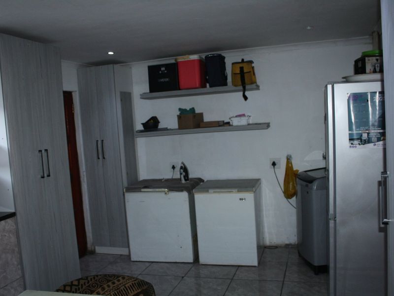 A functional laundry area featuring tiled flooring, built-in cabinetry, and wall-mounted shelving for storage.