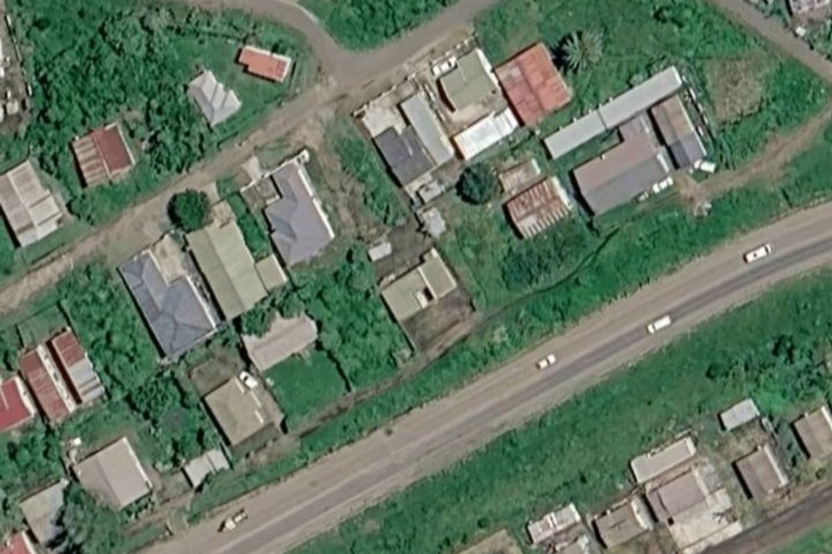 An aerial view of a vacant residential plot surrounded by established neighborhood infrastructure and greenery.