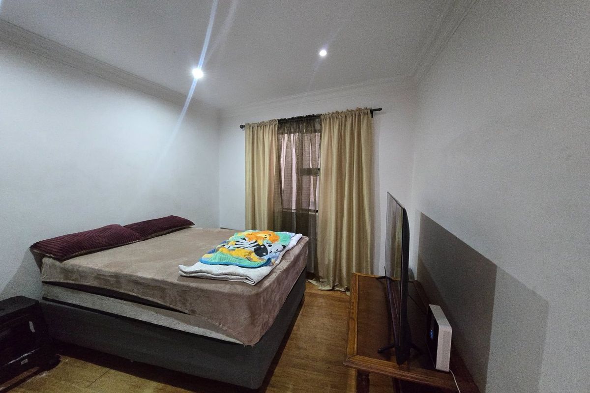 A functional bedroom featuring laminate flooring and recessed downlighting, providing a neutral base for potential interior design updates.