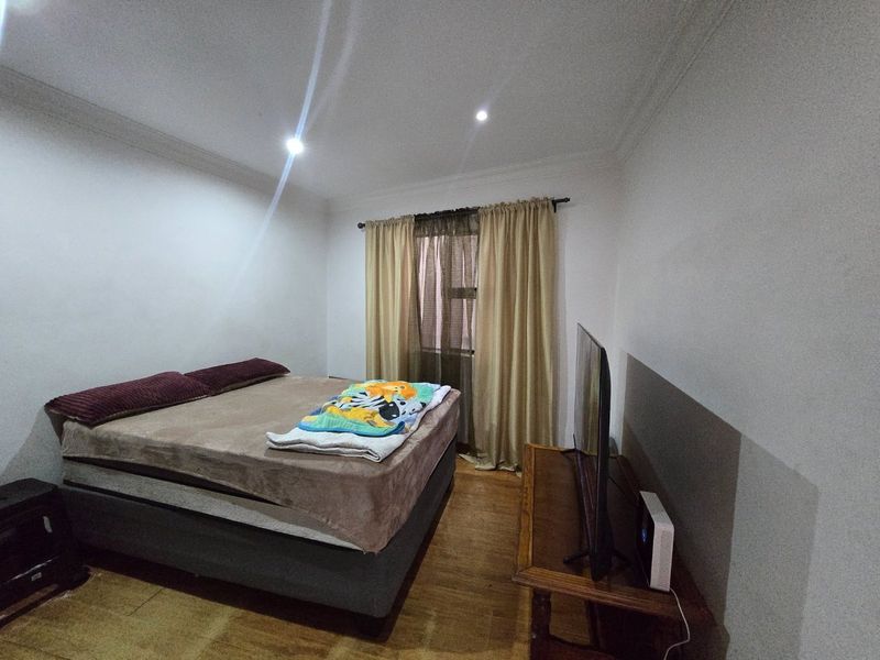 A functional bedroom featuring laminate flooring and recessed downlighting, providing a neutral base for potential interior design updates.