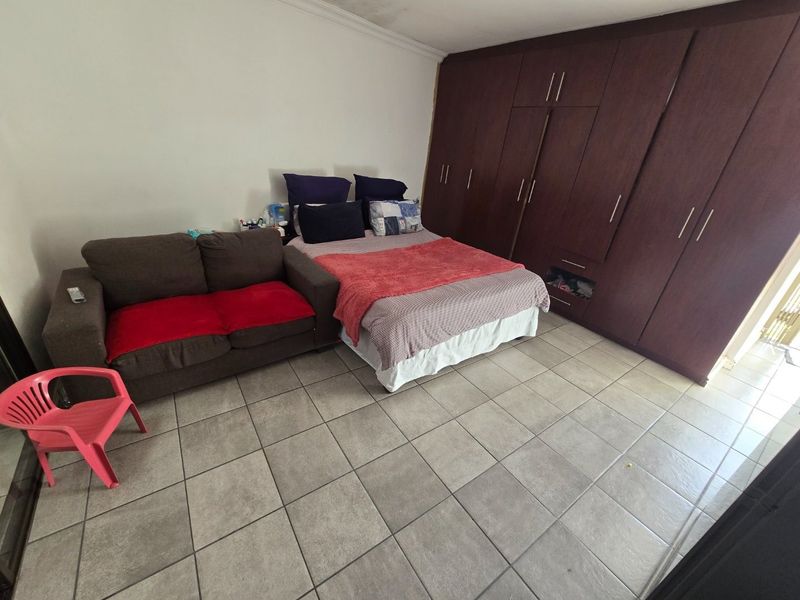 A bedroom featuring tiled flooring and extensive dark wood built-in cupboards for storage.