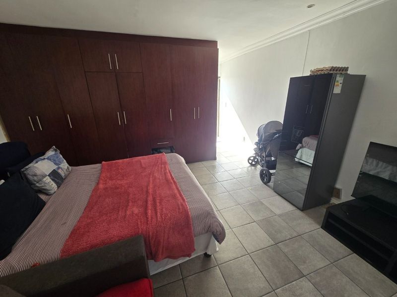 Spacious bedroom featuring extensive dark wood built-in cupboards, neutral tiled flooring, and recessed ceiling lighting.