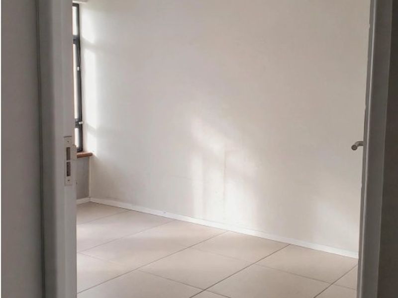 A bright, empty bedroom featuring neutral tiled flooring and a clean, minimalist aesthetic, ready for personalization.
