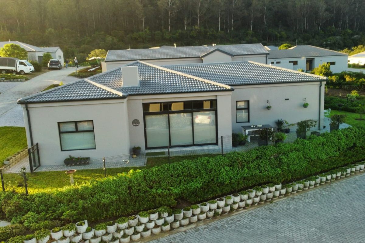 Aerial view of a modern single-story house featuring a tiled roof, paved patio area, and well-maintained garden landscaping in a residential estate setting.