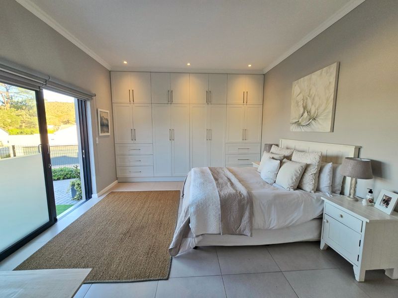 A well-maintained bedroom featuring extensive built-in cabinetry, recessed lighting, and a large sliding glass door providing direct access to the outdoor area.