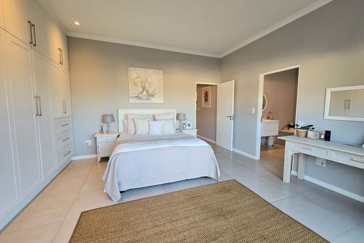 Spacious bedroom featuring neutral tones, extensive built-in cabinetry, tiled flooring, and direct access to an en-suite bathroom.