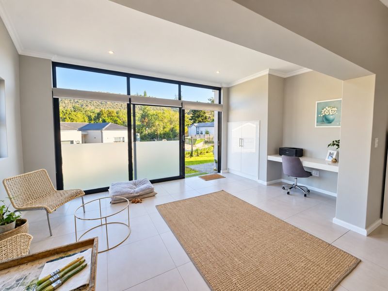 Bright living area featuring large sliding glass doors, tiled flooring, recessed lighting, and a convenient built-in desk and storage unit.