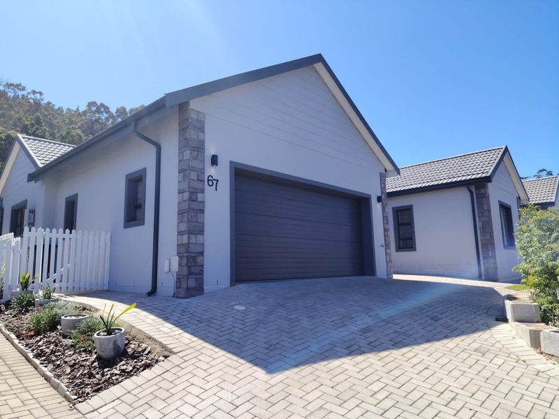 A well-maintained front exterior view of a modern house featuring a paved driveway, stone-accented facade, and a secure garage.