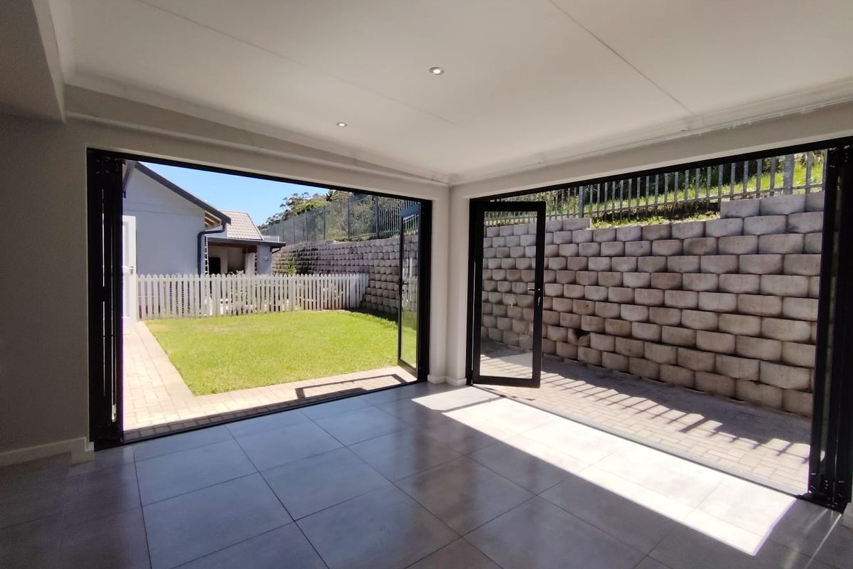 Bright and modern living area featuring large black-framed bi-fold doors that open onto a paved patio and garden space.