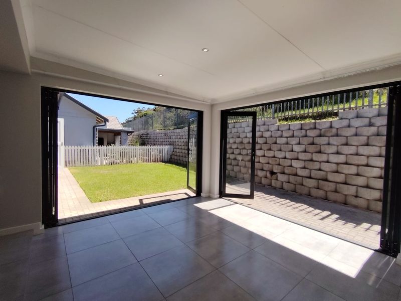 Bright and modern living area featuring large black-framed bi-fold doors that open onto a paved patio and garden space.