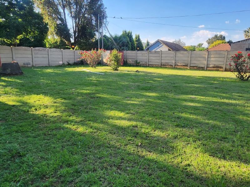 A spacious, level backyard featuring a well-maintained lawn and secure precast concrete boundary walling.