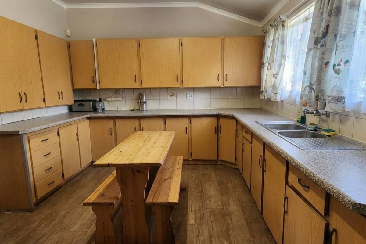 A functional kitchen featuring extensive laminate cabinetry, ample countertop space, a double stainless steel sink, and a tiled backsplash.