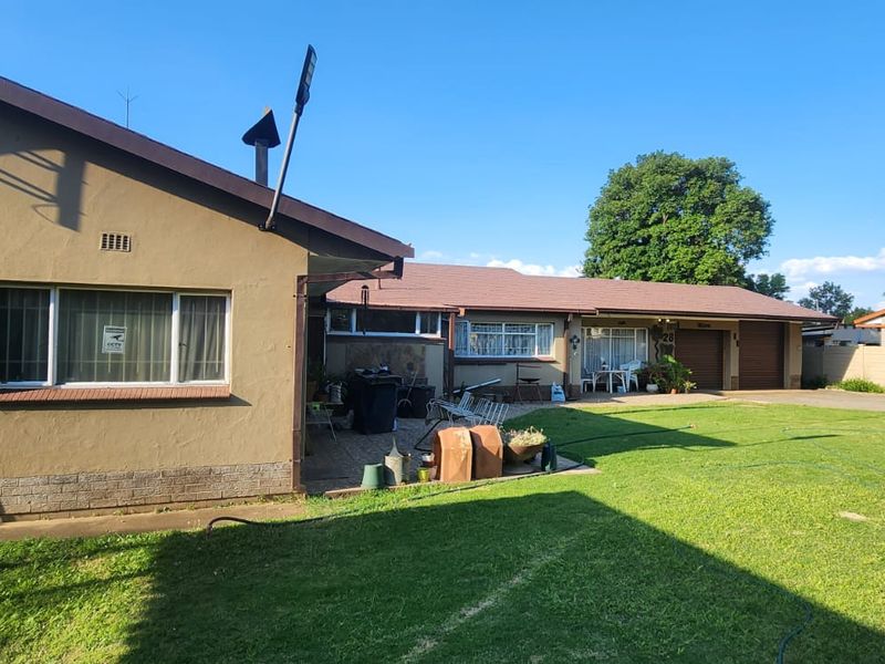 Rear view of the property featuring a paved patio area, a spacious lawn, and access to the garage.