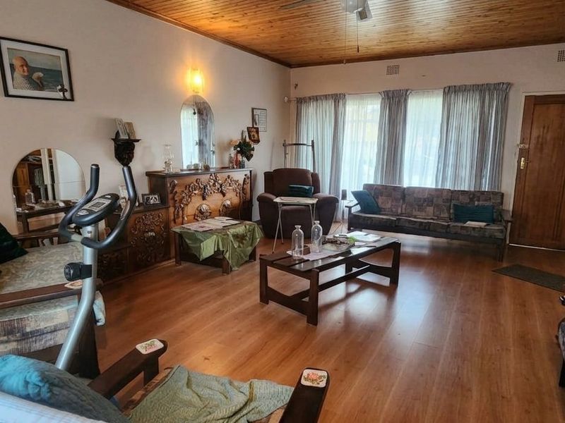 Spacious living room featuring warm laminate flooring and a classic timber tongue and groove ceiling, offering a comfortable and traditional living space.