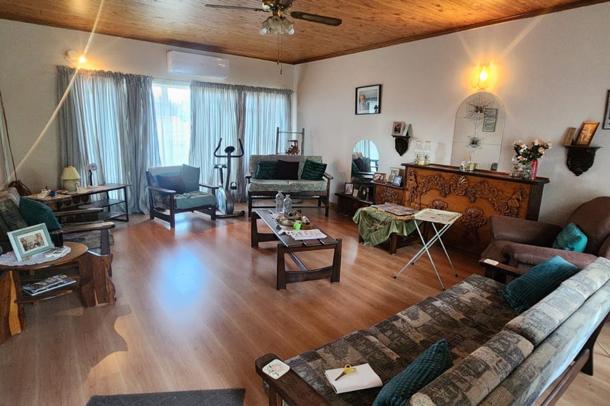 Spacious living room featuring timber ceiling, laminate flooring, and a split-system air conditioner, offering a comfortable and functional living space.