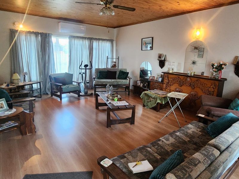 Spacious living room featuring timber ceiling, laminate flooring, and a split-system air conditioner, offering a comfortable and functional living space.