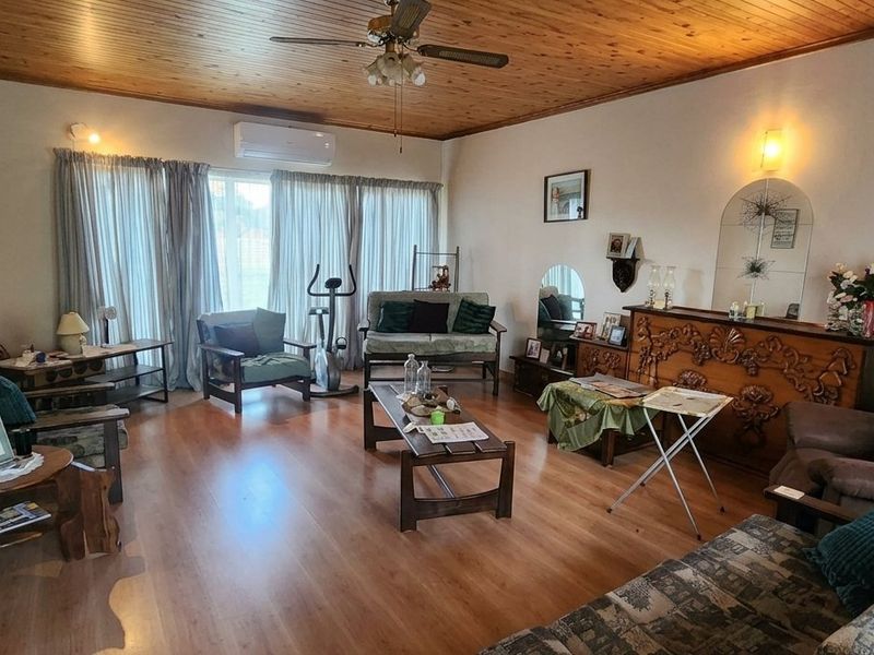 Spacious living room featuring warm timber ceilings, laminate flooring, and a wall-mounted air conditioning unit.