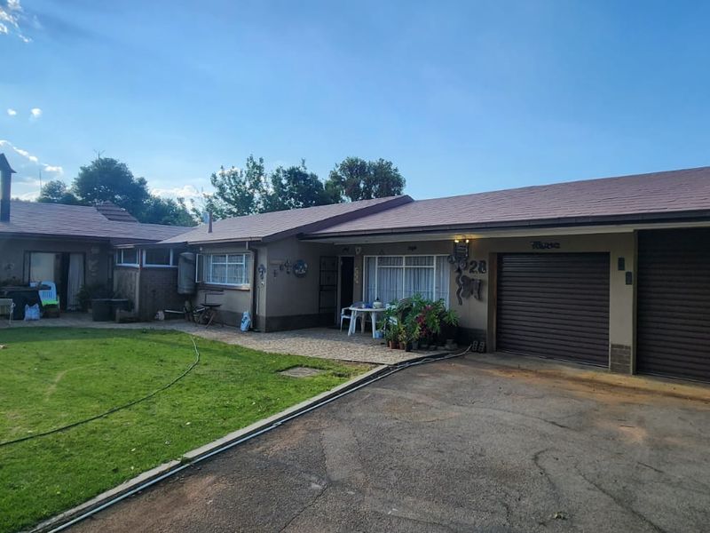 Rear view of the property featuring a double garage, paved driveway, and a paved patio area leading to the garden.