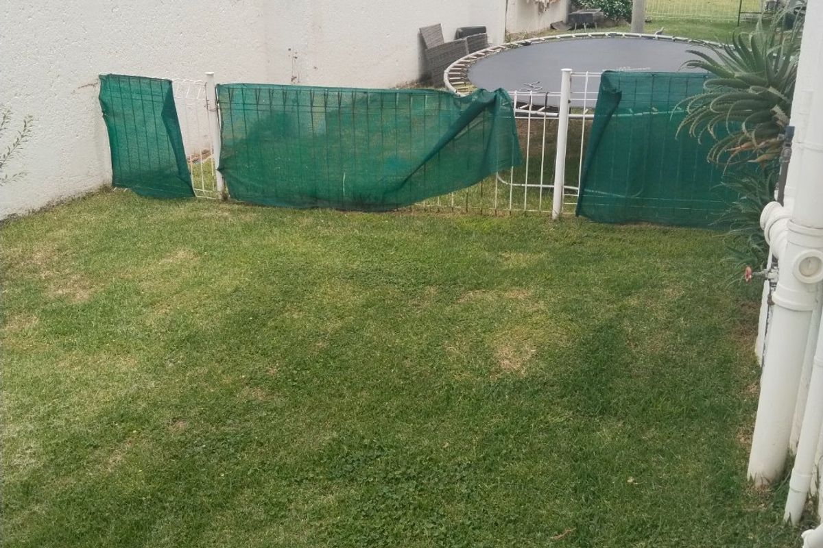 A private rear garden area featuring a lawn, perimeter wall with electric fencing, and external plumbing fixtures.