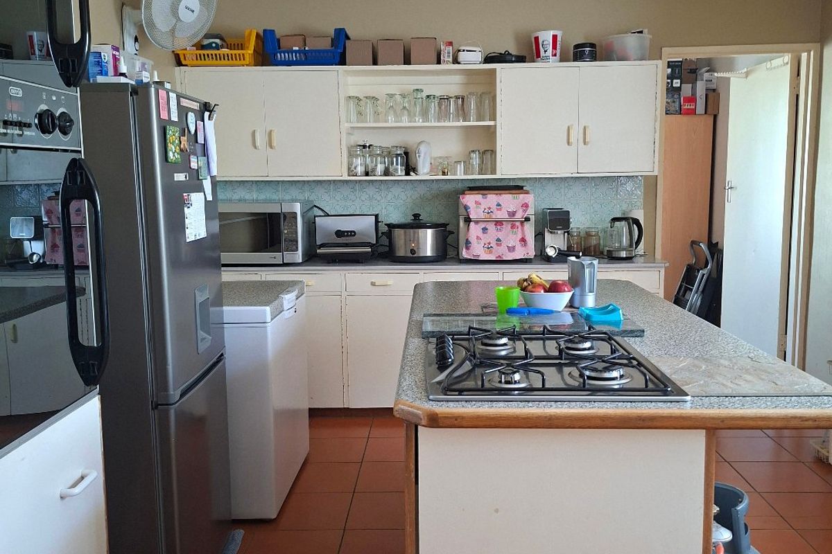 A functional kitchen featuring a central island with a gas hob, built-in oven, ample cabinetry, and tiled flooring throughout.