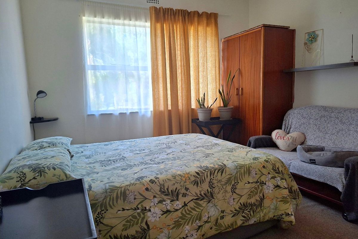 A functional bedroom featuring carpeted flooring and a built-in ventilation vent, offering a comfortable and practical living space.