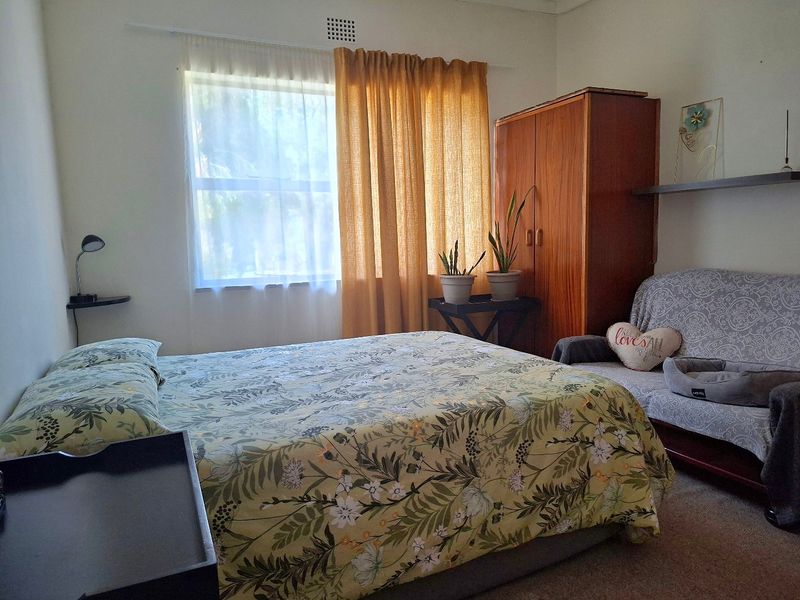 A functional bedroom featuring carpeted flooring and a built-in ventilation vent, offering a comfortable and practical living space.