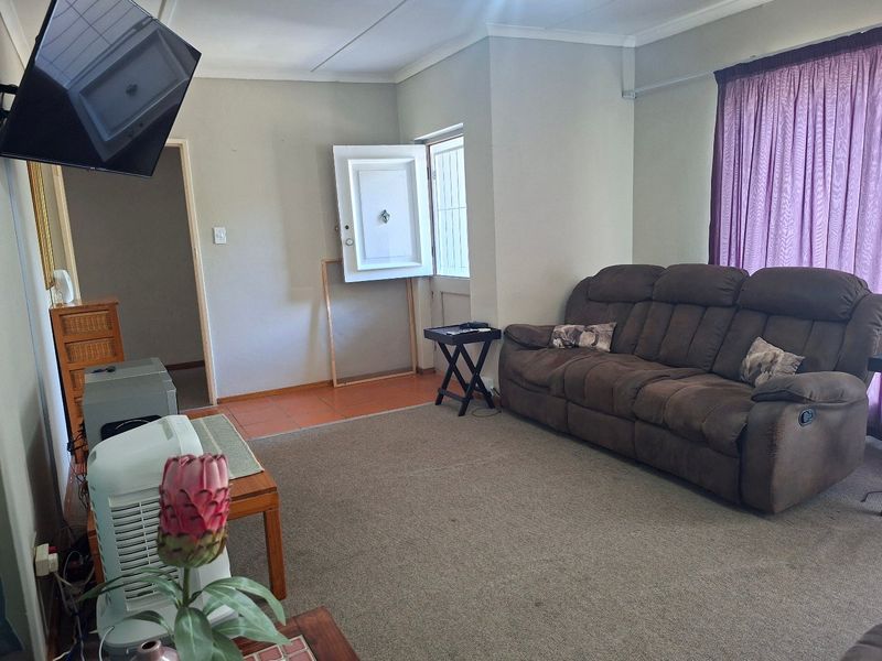A living room area featuring a mix of tiled and carpeted flooring, with access to an exterior door and neutral wall finishes.