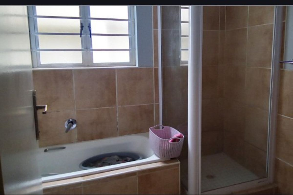 A functional bathroom featuring a built-in bathtub, separate shower enclosure, and tiled wall finishes.