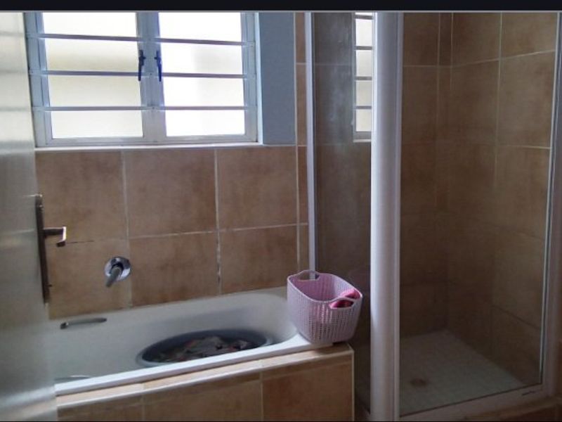 A functional bathroom featuring a built-in bathtub, separate shower enclosure, and tiled wall finishes.