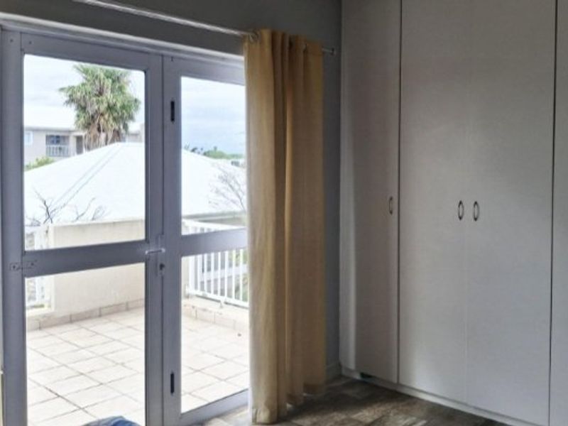 Bedroom featuring built-in cupboards and direct access to a private tiled balcony through double glass doors.
