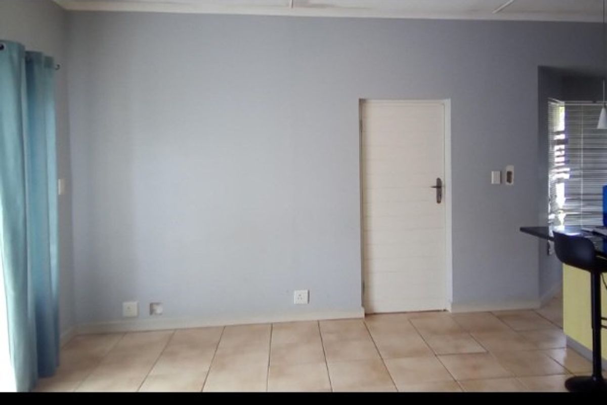 A neutral, tiled living area featuring a clean wall finish, internal door, and ample electrical points, offering a versatile space for interior design.