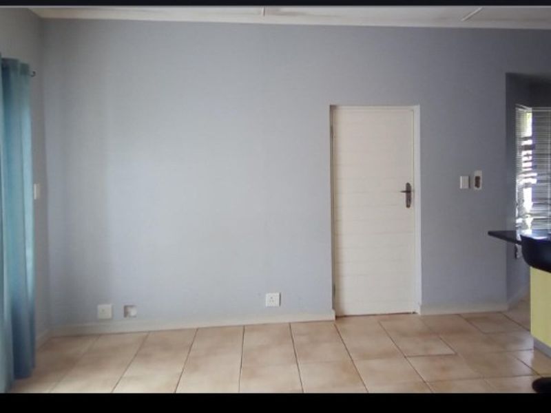 A neutral, tiled living area featuring a clean wall finish, internal door, and ample electrical points, offering a versatile space for interior design.