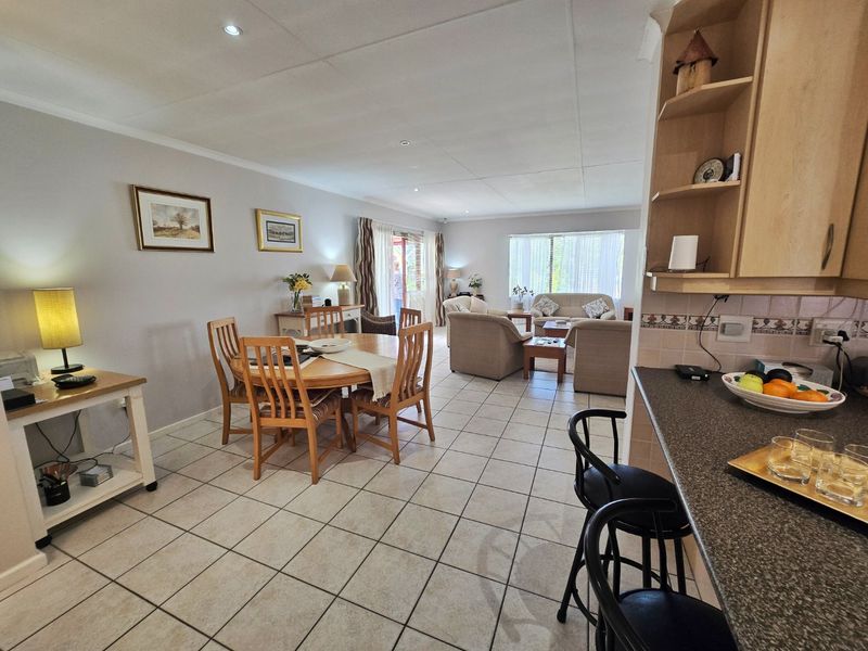 Spacious open-plan living and dining area featuring tiled flooring, recessed lighting, and a functional kitchen with built-in cabinetry and a breakfast bar.