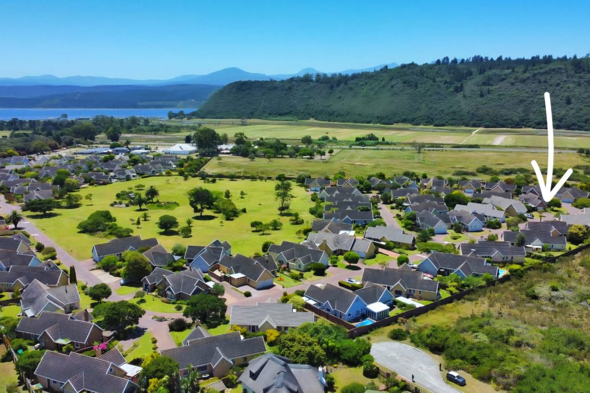 An aerial view of a residential estate featuring multiple homes with tiled roofs, set within a landscaped community near a scenic landscape.