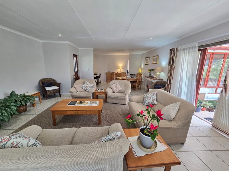 Spacious open-plan living and dining area featuring neutral tiled flooring, recessed lighting, and large sliding glass doors providing access to the outdoor patio.