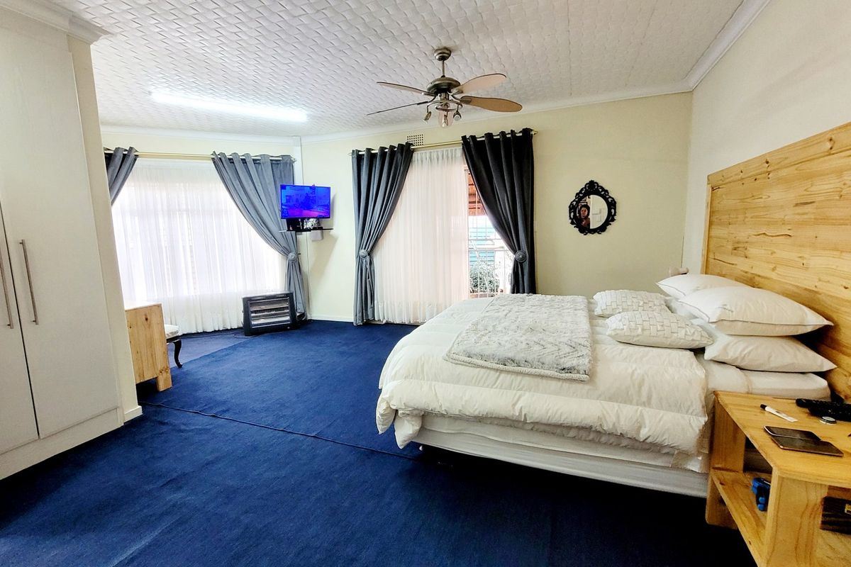 Spacious bedroom featuring a built-in wardrobe, ceiling fan, and textured ceiling, offering a comfortable layout with direct access to natural light.