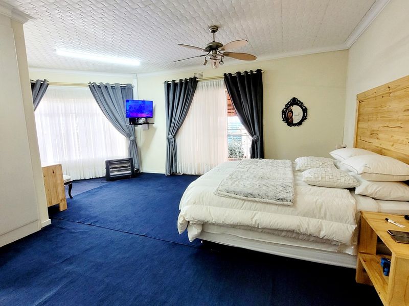 Spacious bedroom featuring a built-in wardrobe, ceiling fan, and textured ceiling, offering a comfortable layout with direct access to natural light.