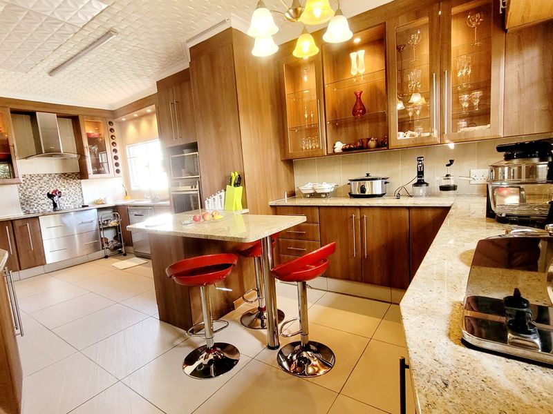 Spacious modern kitchen featuring granite countertops, extensive wood cabinetry, a central island, and integrated stainless steel appliances.